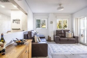 Ein modernes Wohnzimmer mit einer Couch, einem Couchtisch und einem Essbereich mit einer Flasche und einer Schüssel.