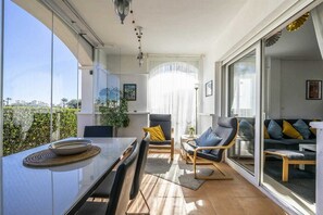 Ein modernes Wohnzimmer mit Glastür zum Balkon, einem Essbereich mit Tisch und Stühlen sowie einer Sofagarnitur.