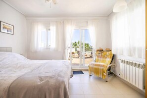 Ein Hotelzimmer mit einem Bett, einem Sessel mit Decke, Blick ins Freie und einem Heizkörper.