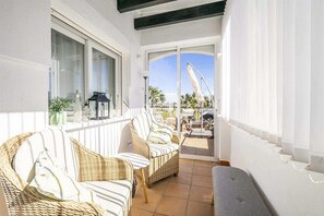 Ein Balkon mit Korbmöbeln, Blick aufs Meer und ein klarer Himmel.
