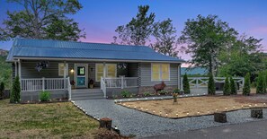 A log cabin with a porch, a front door, and a small garden area with decorative lights. - New Luxurious Mountain Escape with Spa & Views (Sugar Mountain)