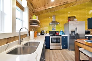 A modern kitchen with stainless steel appliances, a wooden ceiling, and yellow tiled backsplash. - New Luxurious Mountain Escape with Spa & Views (Sugar Mountain)