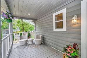 A covered porch with wicker chairs, a small table, and a potted plant. - New Luxurious Mountain Escape with Spa & Views (Sugar Mountain)