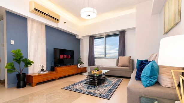 Een woonkamer met een televisie, bank en een groot raam.