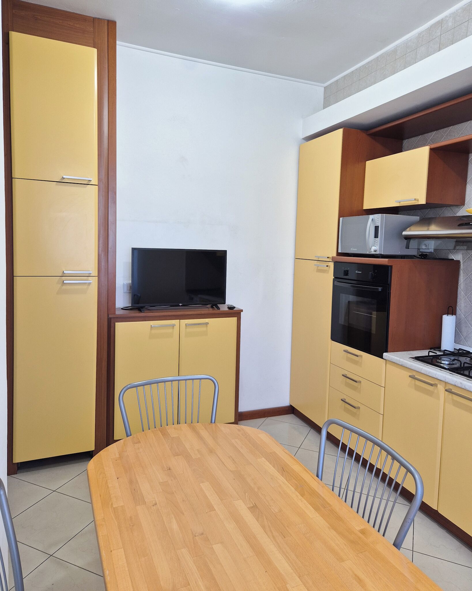 Una cocina compacta con mesa, sillas, televisor, microondas y estufa.