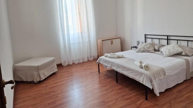 Ein Schlafzimmer mit einem Bett, einem Nachttisch, einem Holzschrank und einer kleinen Bank.