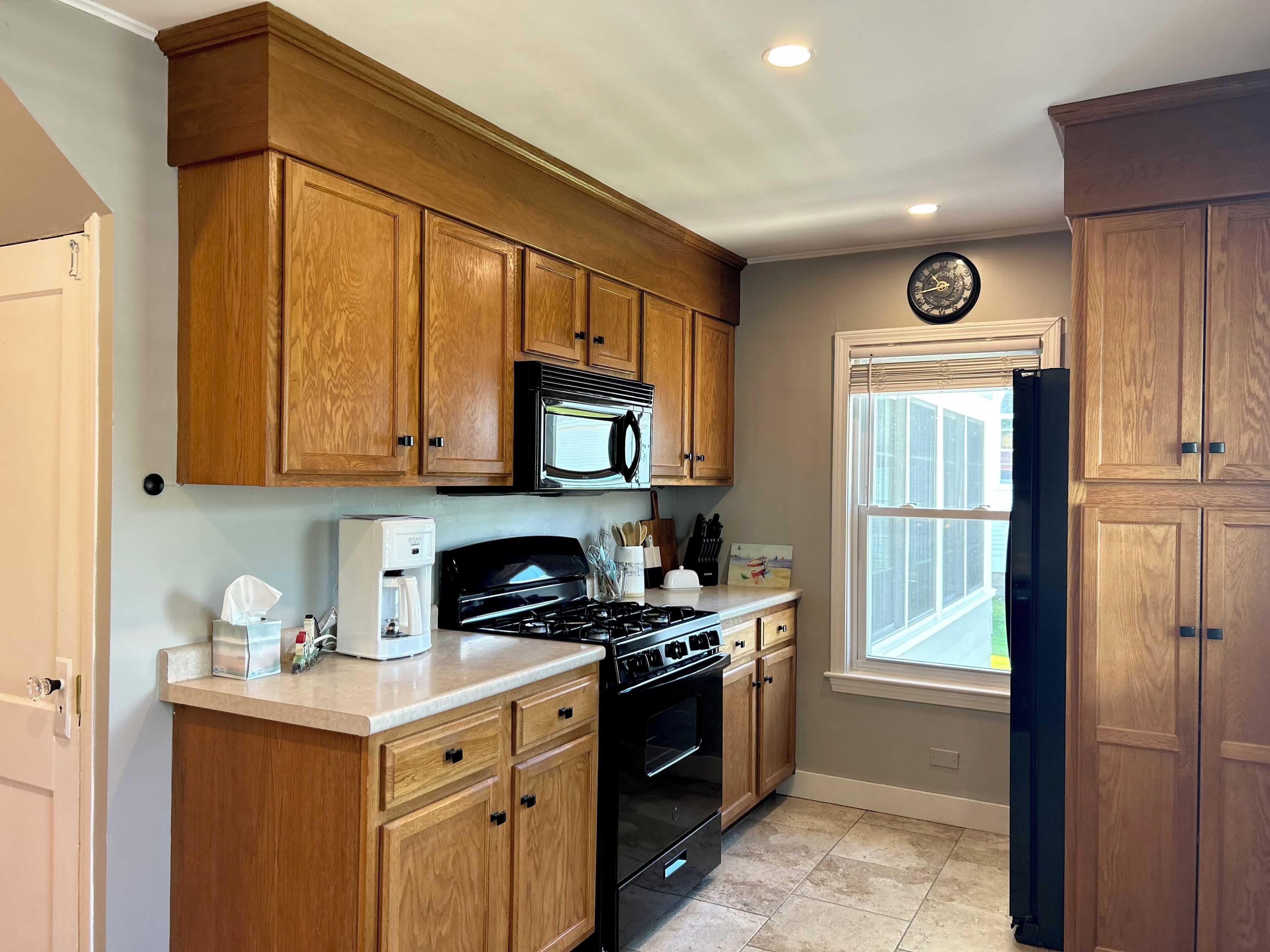 Una cocina con armarios de madera, estufa, microondas y refrigerador.