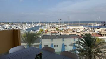 Eine Terrasse mit Tisch und Stühlen mit Blick auf eine Marina, in der Boote liegen, und eine Baustelle.