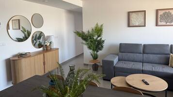Ein modernes Wohnzimmer mit einem grauen Sofa, runden Spiegeln und einem Essbereich mit Tisch und Stühlen.