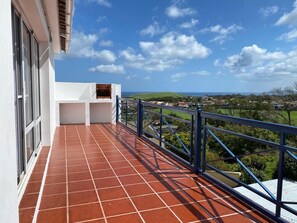 Ein Balkon mit roten Ziegeln, einer weißen Wand und einem blauen Geländer.