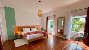 Ein Schlafzimmer mit Bett, einer Pendelleuchte, einem Sessel und einem Fenster mit Blick.