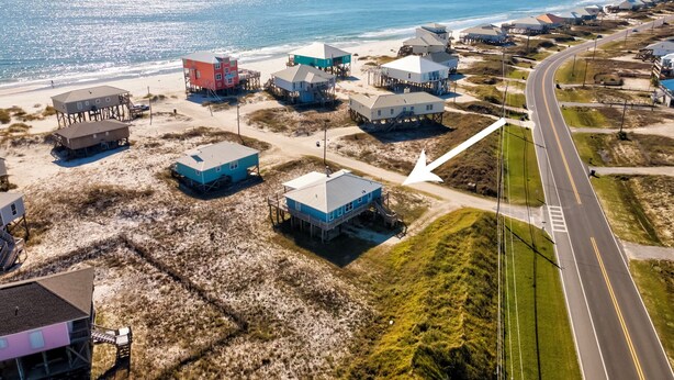An aerial view of a coastal area with buildings on stilts, a road, and the ocean in the background. - Sea Glass, Gulf Beachside, 3/2, Sleeps 9 (Dauphin Island)