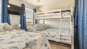 A room with bunk beds, a flat-screen TV, and a window with curtains. - Sea Glass, Gulf Beachside, 3/2, Sleeps 9 (Dauphin Island)
