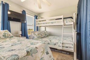 A room with bunk beds, a flat-screen TV, and a window with curtains. - Sea Glass, Gulf Beachside, 3/2, Sleeps 9 (Dauphin Island)