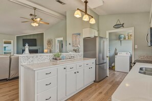 A modern kitchen with a central island, stainless steel appliances, and a ceiling fan. - Sea Glass, Gulf Beachside, 3/2, Sleeps 9 (Dauphin Island)