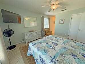 A bedroom with a bed, dresser, fan, ceiling fan, window, and door. - Sea Glass, Gulf Beachside, 3/2, Sleeps 9 (Dauphin Island)