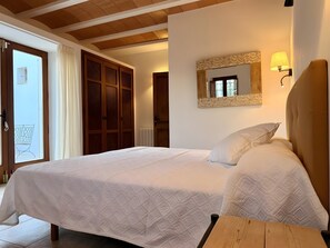 A bedroom with a bed, a wooden headboard, a wall-mounted mirror, and a view of a balcony.