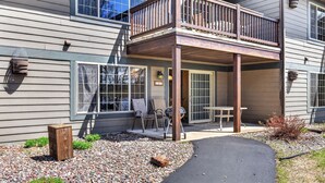 Ein zweigeschossiges Haus mit überdachter Terrasse, einer kleinen Holzterrasse und einem Kiesweg, der zum Eingang führt.