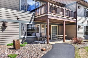 A two-story house with a covered patio, a small deck, and a gravel pathway leading to the entrance. - Lake front 2-bedroom on Eagle River Chain of Lakes with indoor pool and jacuzzi! (Eagle River)