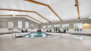 Ein Hallenbad mit klarem Wasser, Holzbalken an der Decke und mehreren Fenstern.