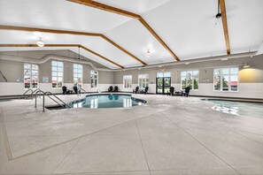 An indoor swimming pool with clear water, wooden beams on the ceiling, and multiple windows. - Lake front 2-bedroom on Eagle River Chain of Lakes with indoor pool and jacuzzi! (Eagle River)