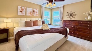 Ein Schlafzimmer mit einem großen Bett, einem Nachttisch, einer Kommode und einem Deckenventilator.