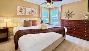 A bedroom with a large bed, a nightstand, a dresser, and a ceiling fan. - Amazing Home Near Parks w/ Pool & Spa (Kissimmee)