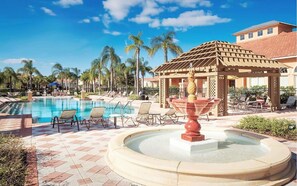 Un'area piscina con lettini, un gazebo e palme.