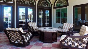 Eine Terrasse mit einem runden Tisch, vier Stühlen und einem Deckenventilator.