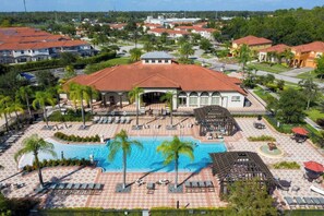 Un resort con piscina centrale, lettini prendisole e una zona porticata.