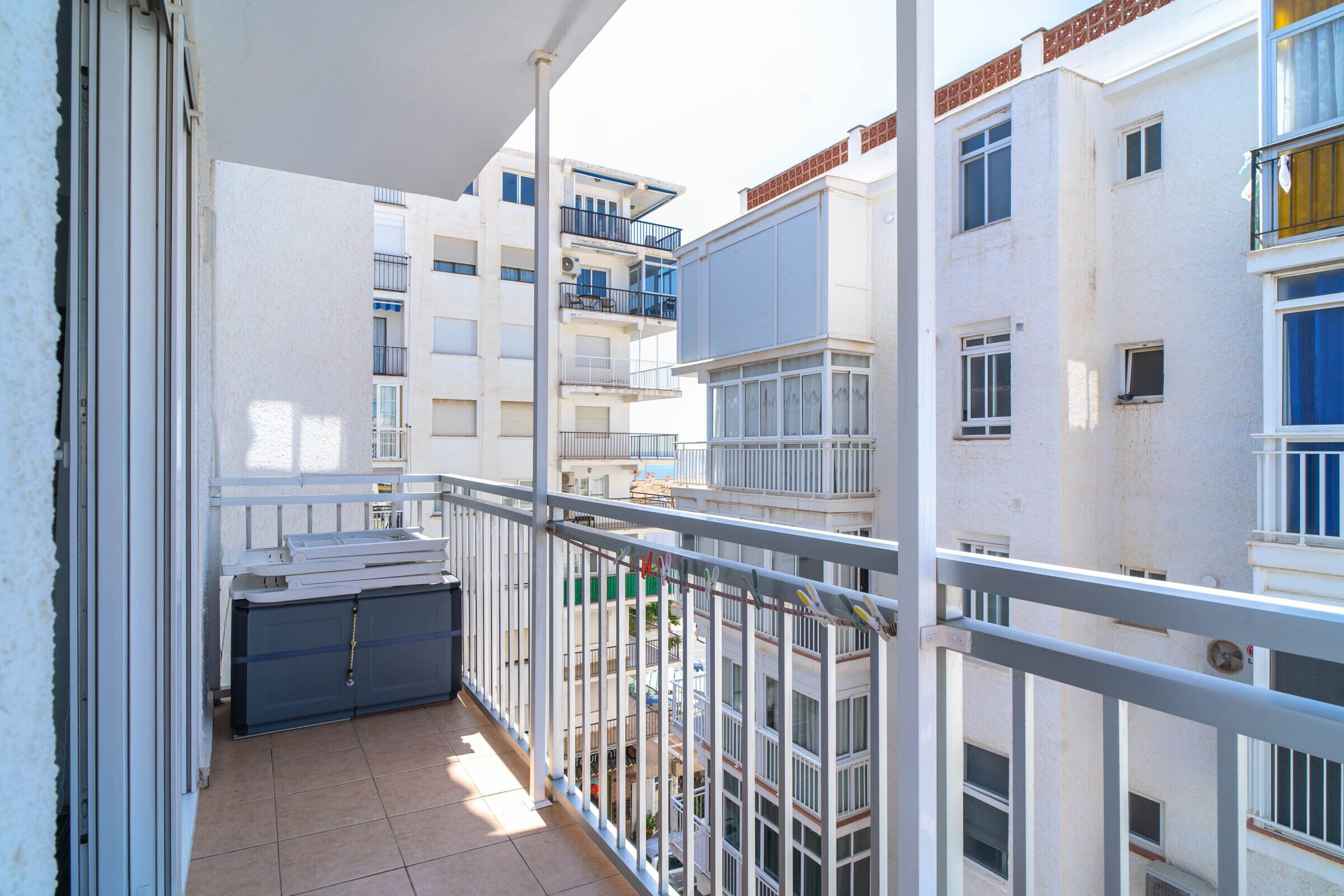 Un balcone con vista sugli edifici circostanti, una ringhiera in metallo e una porta chiusa.