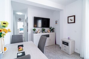 Ein moderner Essbereich mit Flachbildfernseher, einem kleinen Schrank und einem Esstisch mit Stühlen.
