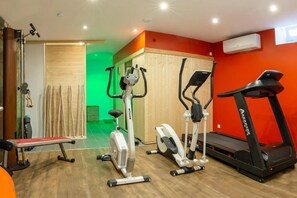 A home gym with an elliptical, a stationary bike, a treadmill, and a bench. - Villa Maeva – Loft with Parking, Sauna & Fitness Room (Riquewihr)