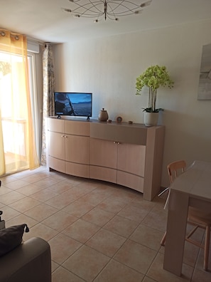A modern living room with a TV, a dining table, and a sofa. - 2-room apartment, 45 m², ground floor, garden 50 m² + terrace 26 m² (Hyères)