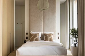 A modern hotel room with a large bed, a pendant light, and a potted plant. - Luxurious Suite - AC- 2P- Madeleine/saint Honore (Paris)