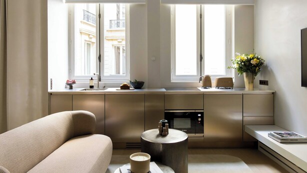 A modern kitchen with a built-in oven, a dining area with a bench, and a view of the city through large windows. - Luxurious Suite - AC- 2P- Madeleine/saint Honore (Paris)