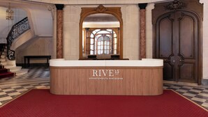A reception area with a check-in counter, a staircase, and a large wooden door. - Luxurious Suite - AC- 2P- Madeleine/saint Honore (Paris)