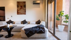 A modern living room with a sofa, a glass coffee table, and a potted plant. - Prestigia Golf Resort |Luxury 3BR| Pool&Atlas View (Marrakesh)