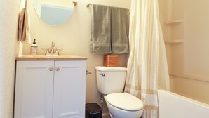 Ein Badezimmer mit Toilette, Waschbecken, Spiegel und Duschvorhang.