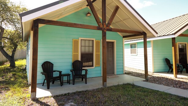 Ein Haus mit Veranda, zwei Stühlen und einem kleinen Tisch.