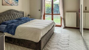 Een slaapkamer met een bed, een radiator, een raam met gordijnen en een schilderij aan de muur.
