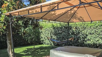 A covered outdoor area with a hammock, a large inflatable mattress, and a tree.
