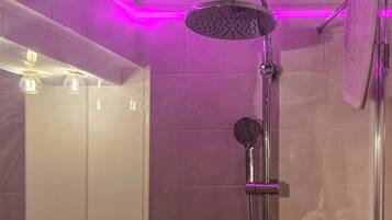 A bathroom with a glass-enclosed shower, a mirror, and a towel rack.