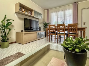 Ein Wohnzimmer mit Fernseher, Holzmöbeln und Zimmerpflanzen.