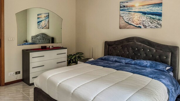 A bedroom with a bed, a dresser, a mirror, and two paintings on the wall.