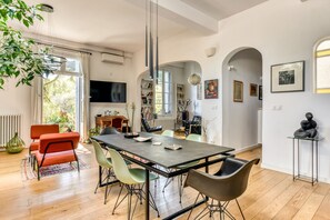 A modern dining area with a long table, chairs, and a television. - Les Jardins des Arceaux - Premi re Conciergerie (Montpellier)