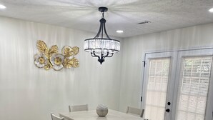 Un comedor con una mesa, sillas, una araña y un adorno mural.