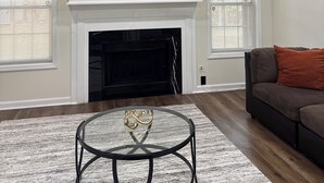 Una sala de estar con chimenea, ventilador de techo, televisor de pantalla plana y un sofá.