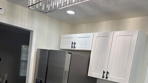 Una cocina moderna con armarios blancos, electrodomésticos de acero inoxidable y salpicadero de azulejos.