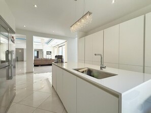 A modern kitchen with a large island, stainless steel appliances, and a hanging light fixture.